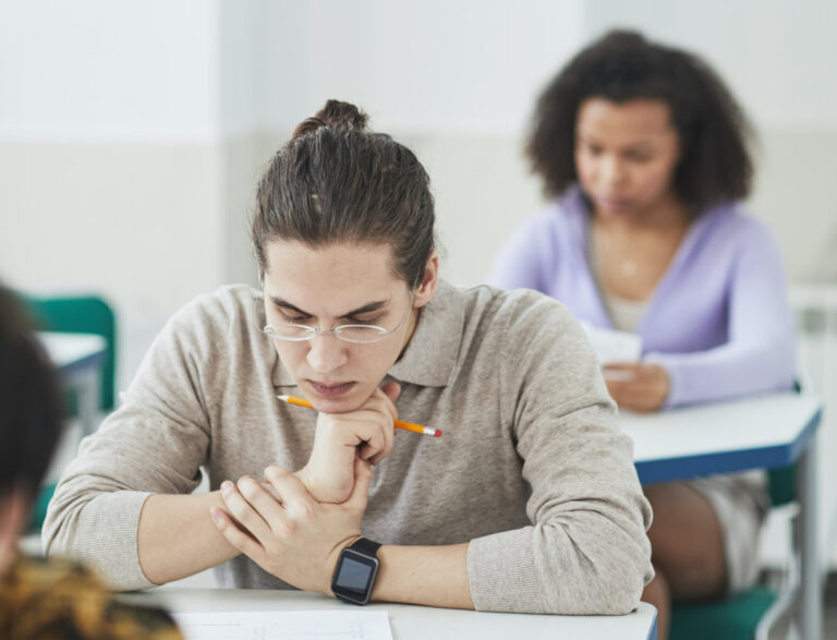 A man with his hand on his chin sits at a desk