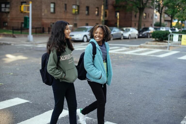 Two young girls are crossing the street