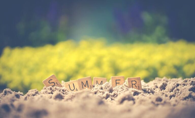 Beach sand with scrabble letters forming the word "summer,"